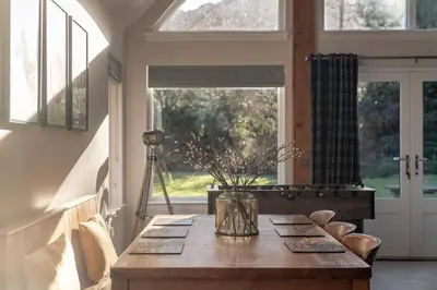 a dining room with a table with a vase on it at Scenic Oaklodge with wood burner in Saint Fillans