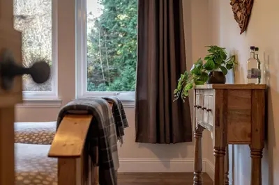 a living room with a window and a wooden table at Scenic Oaklodge with wood burner in Saint Fillans