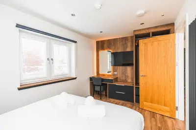 a bedroom with a bed and a desk and a television at Jackton Distillery Steadings in Busby