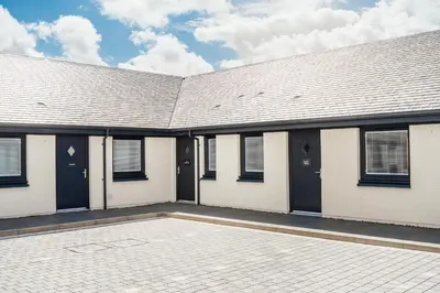 a building with black doors and a tile courtyard at Jackton Distillery Steadings in Busby