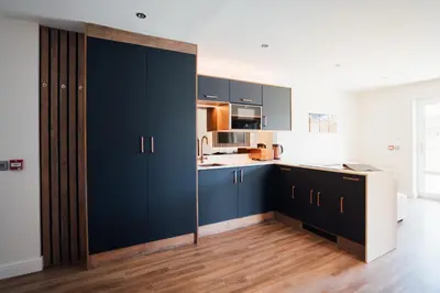 a kitchen with navy blue cabinets and wooden floors at Jackton Distillery Steadings in Busby