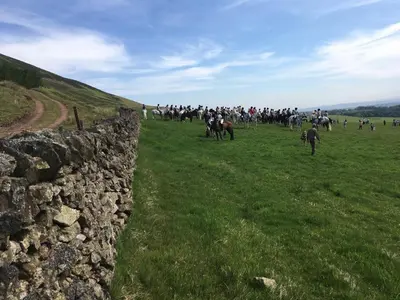 a large group of people riding horses in a field at Garden Retreat in Nine Mile Burn