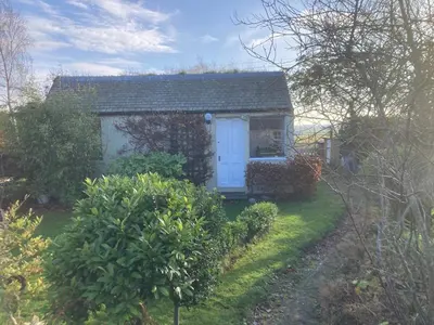 a small house with a blue door in a yard at Garden Retreat in Nine Mile Burn