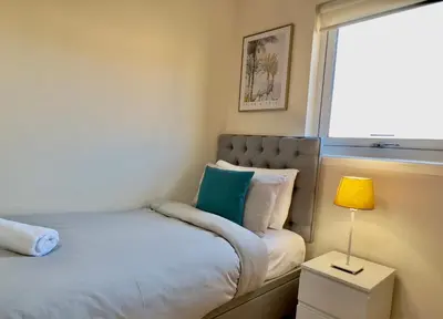 a small bedroom with a bed and a window at Sleek & Modern 2BR - Easy Access to City Centre in Glasgow
