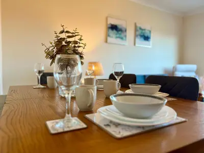 a wooden table with plates and wine glasses on it at Sleek & Modern 2BR - Easy Access to City Centre in Glasgow