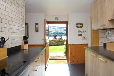 a kitchen with a door leading to a yard at Ivy Tree Cottage in Morenish