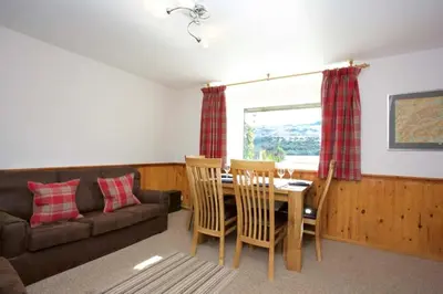 a living room with a couch and a table and chairs at Ivy Tree Cottage in Morenish