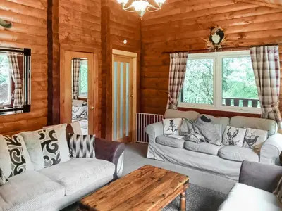 a living room with two couches and a table at Grouse Lodge in Dunoon