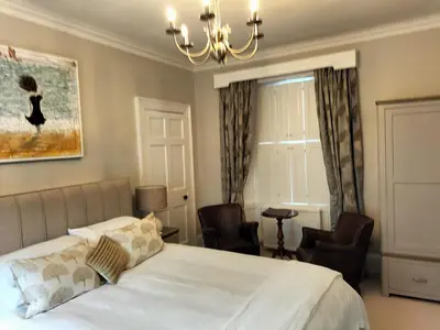 a bedroom with a bed with chairs and a chandelier at Park Cottage - Spacious & Luxurious Room in B Listed Cottage in Moffat
