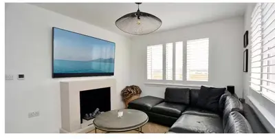 a living room with a black couch and a flat screen tv at West Coast Home From Home in Stevenston