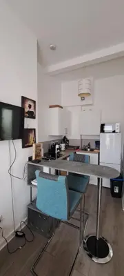 a kitchen with a table and two blue chairs at Cozy, modern flat in Govan in Glasgow