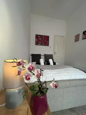 a bedroom with a bed and a table with flowers at Cozy, modern flat in Govan in Glasgow