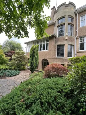a large brick building with windows and bushes at Home away from home in Glasgow - Free Street Parking in Mansewood