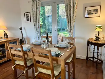 a dining room with a table and chairs and a window at Cosy Karibu cottage with stunning canal views in Cairnbaan
