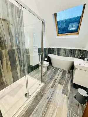 a bathroom with a shower and a tub and a sink at The Bell Tower in Bonnybridge