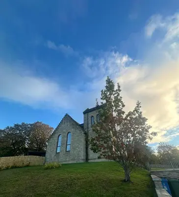 an old church with a tree in front of it at The Bell Tower in Bonnybridge