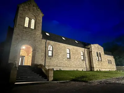 a large stone building with stairs in front of it at The Bell Tower in Bonnybridge