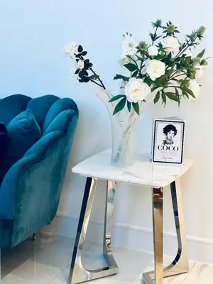 a vase of flowers on a table next to a chair at The Bell Tower in Bonnybridge