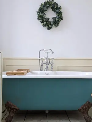 a bath tub in a bathroom with a wreath on the wall at Mulberry Lodge Guest Suite - luxurious accommodation on West Highland Way in Drymen