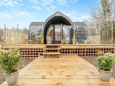 a wooden deck with a gazebo in a yard at Woodland Pod in Leadburn