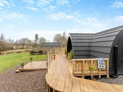 a wooden deck in front of a black building at Woodland Pod in Leadburn