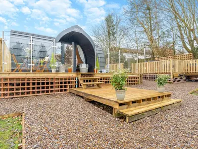 a patio with wooden benches and a building at Woodland Pod in Leadburn