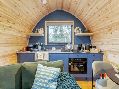 a living room with a couch and a kitchen at Woodland Pod in Leadburn