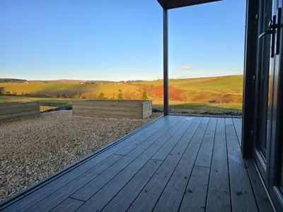 a wooden deck with a view of the countryside at West Riverside Farm in Stirling