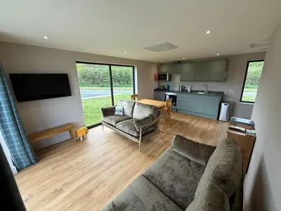 a living room with a couch and a kitchen at Loganlea Lodge in Loanhead