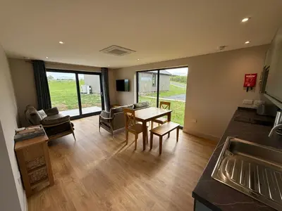a kitchen and living room with a table and chairs at Loganlea Lodge in Loanhead