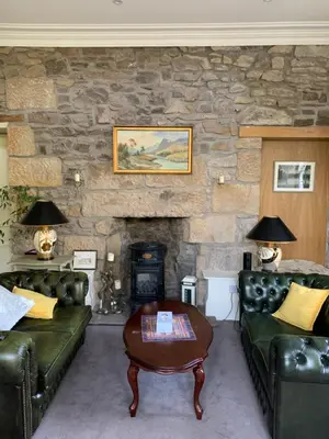 a living room with couches and a stone fireplace at Creity Hall Guest House in Doune