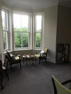 a living room with chairs and a table and windows at Creity Hall Guest House in Doune