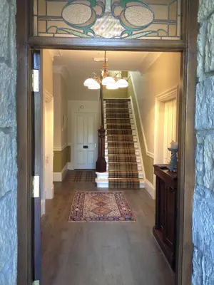 a hallway with a staircase in a house with a glass door at Creity Hall Guest House in Doune