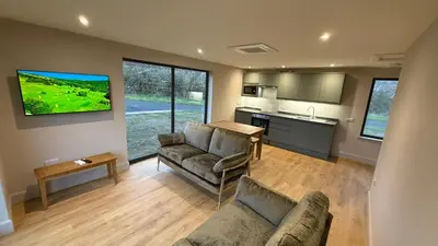 a living room with a couch and a table and a kitchen at Threipmuir Lodge in Loanhead
