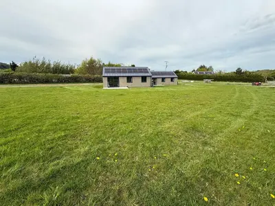 a house with a large green field with a building at Threipmuir Lodge in Loanhead