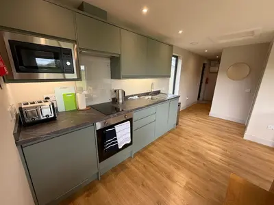a kitchen with stainless steel appliances and wooden floors at Threipmuir Lodge in Loanhead
