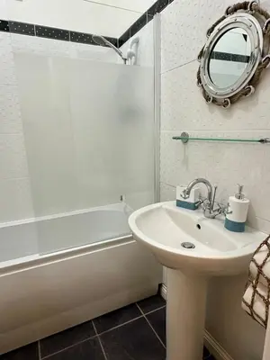a bathroom with a sink and a mirror and a tub at Sea Ayr - City Centre Apartment in Ayr