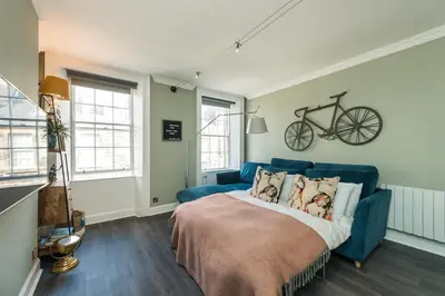 a bedroom with a blue couch and a bike on the wall at The Cobbled Rider in Edinburgh