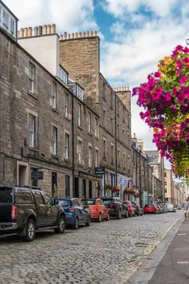 a street with cars parked on a cobblestone street with buildings at The Cobbled Rider in Edinburgh
