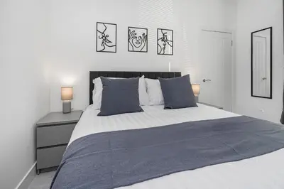 a white bedroom with a large bed with blue pillows at Coaledge Coorie - A wee find in Fife in Fordell