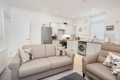 a living room with a couch and a kitchen at Coaledge Coorie - A wee find in Fife in Fordell