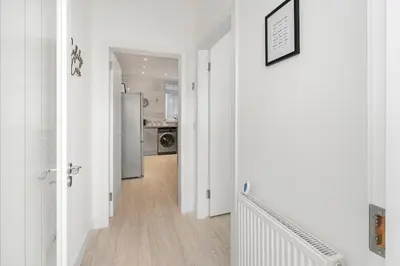 a hallway with white walls and a kitchen with a refrigerator at Coaledge Coorie - A wee find in Fife in Fordell