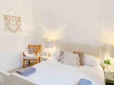 a white bedroom with a large bed and a chair at Chic flat close to Edinburgh, Airport, & Zoo in Edinburgh
