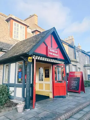 a small store with a red door on a street at Chic flat close to Edinburgh, Airport, & Zoo in Edinburgh
