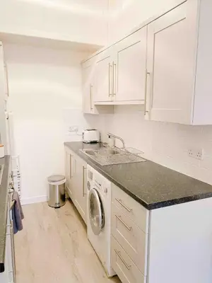 a white kitchen with a sink and a dishwasher at Chic flat close to Edinburgh, Airport, & Zoo in Edinburgh