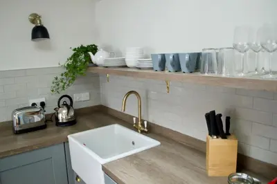 a kitchen counter with a sink and plates on a shelf at The Muse in Edinburgh