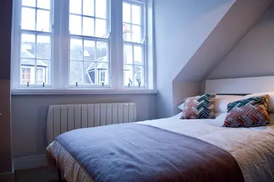 a bedroom with a bed with two pillows and two windows at The Muse in Edinburgh