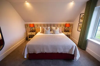 a bedroom with a large white bed with two windows at Heather Lodge in Comrie