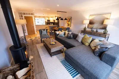 a living room with a couch and a stove at Heather Lodge in Comrie