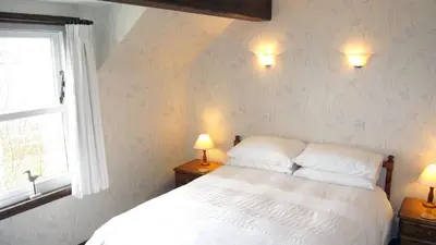 a bedroom with a white bed and two lamps at Craobh Haven Cottages in Craobh Haven